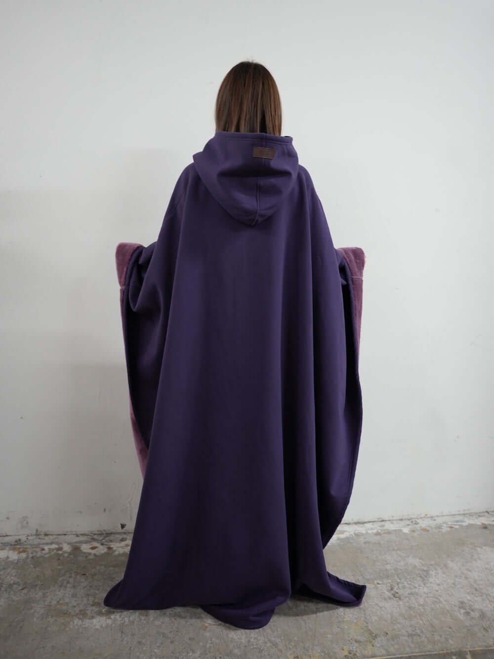 Cozy Eden Comfort Hoodie Blanket in purple, offering relaxation and stress relief, worn backwards by a model.