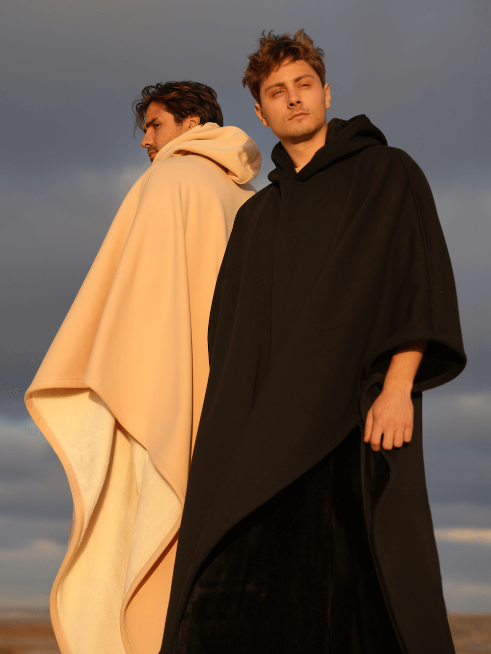 Two models showcasing the Eden Comfort Hoodie Blanket in black and beige, designed for relaxation and comfort.