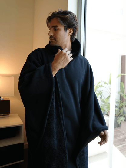 Man wearing the Eden Comfort Hoodie Blanket, showcasing relaxation and cozy style in a modern indoor setting.  Oversized Comfort Hoodie Blanket – Wearable Sherpa Fleece for Cozy Warmth    qykyai-sq.myshopify.com